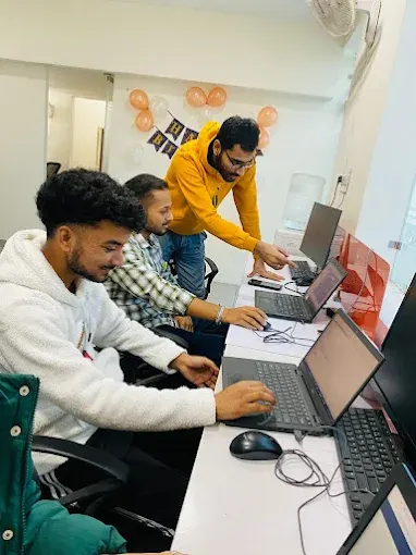 A Dzimark mentor guiding students on their laptops during a class